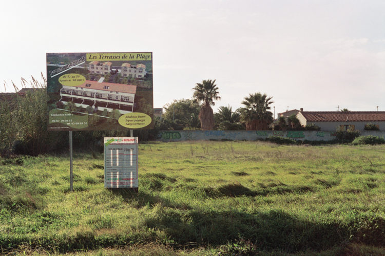 Franck Pourcel | La petite mer des oubliés – Paradoxes | 1996-2006 | Paradoxes | Photographie en couleur d'un terrain proche de la plage du Jaï avec un panneau d'une future construction sur un terrain vide